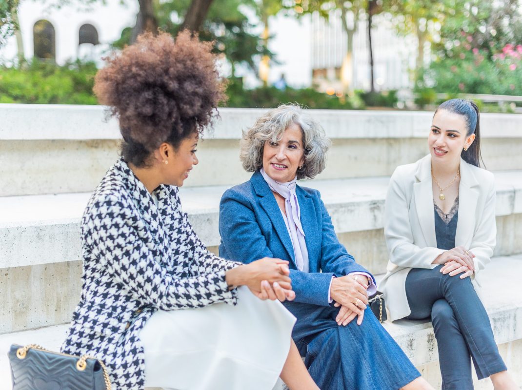 three female workers talking business while sitting in the street three female co-workers talking business while sitting in the street, horizontal close up